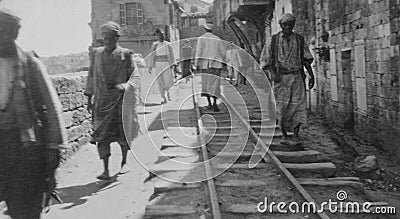 1920s monochrome photo of a street scene with people walking on the railway line, at the Quay in Jaffa in Palestine, now Israel. Editorial Stock Photo