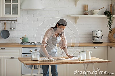 30s woman leaning over table, rolling out dough. Stock Photo