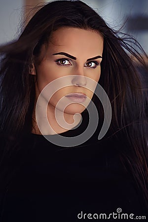 25s woman portrait with fluttering black hairs looking at camera posing indoors Stock Photo