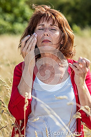 50s woman suffering from rhinitis or hay fever outdoors Stock Photo
