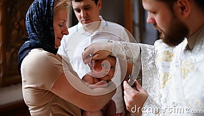 The sacrament of baptism. Christening the baby. Child, priest and godfather Stock Photo