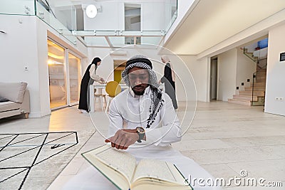 In the sacred month of Ramadan, an African American Muslim man engrossed in reading the Holy Quran is surrounded by a Stock Photo