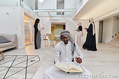 In the sacred month of Ramadan, an African American Muslim man engrossed in reading the Holy Quran is surrounded by a Stock Photo