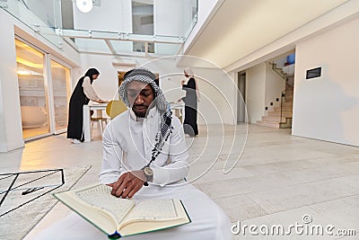 In the sacred month of Ramadan, an African American Muslim man engrossed in reading the Holy Quran is surrounded by a Stock Photo