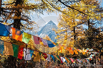 Sacred Xiannairi mountain with colorful prayer flags blowing in autumn forest Stock Photo