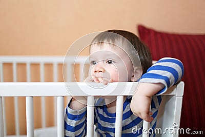 Sad 1 year baby in white bed Stock Photo