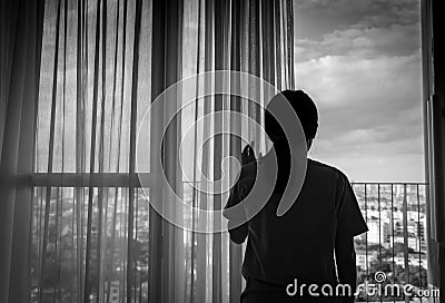 Sad adult Asian woman looking out of window and thinking. Stressed and depressed young woman. Despair women with long hair Stock Photo