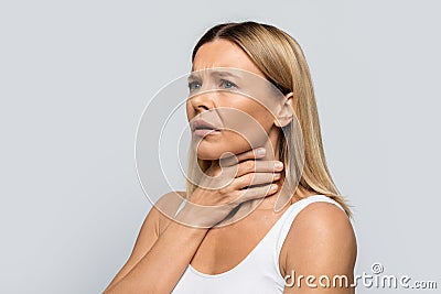 Sad adult blonde woman touching her neck, copy space Stock Photo