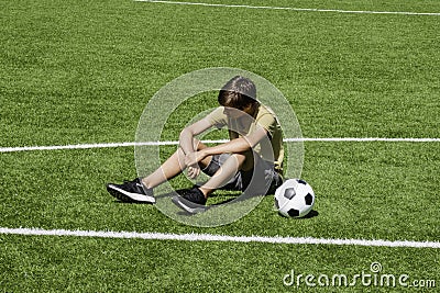 Sad alone teenage boy sitting in empty school sport stadium outdoors. Emotions, defeat, lost game, difficulties Stock Photo