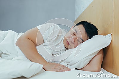 Sad Asian lying in a bed under a blanket, a depressed man in the morning Stock Photo