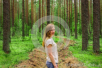 Sad attractive woman among trees in a forest clearing Stock Photo