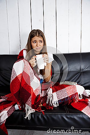 Sad beautiful girl watching tv, sitting on sofa at home. Stock Photo