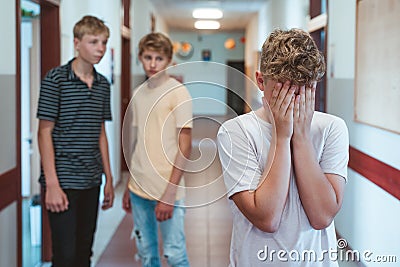 Sad bullied boy standing n the school corridor Stock Photo