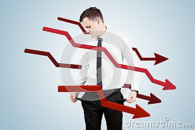 Sad businessman standing with declining arrows Stock Photo