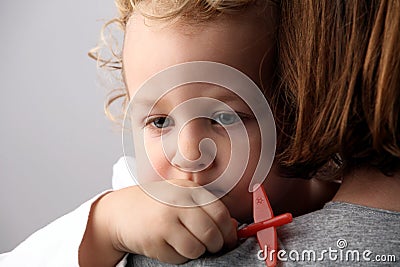 Sad child with blond curly hair holding a plane on mothers hands. Stock Photo