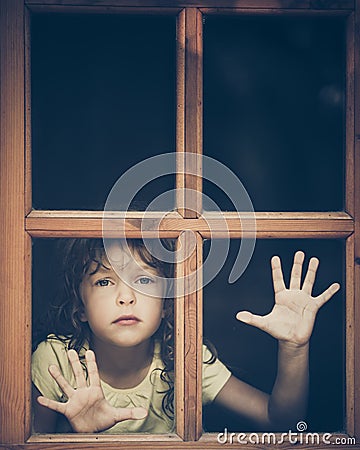 Sad child looking out the window Stock Photo