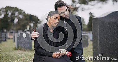 Sad couple, rose and graveyard in loss, grief or mourning at funeral, tombstone or cemetery. Man and woman hug with Stock Photo