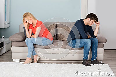 Sad Couple Sitting Back To Back On Sofa Stock Photo