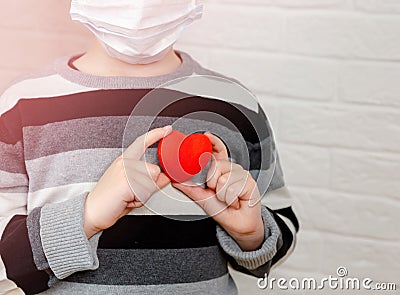 Sad and desperate child boy holding red toy heart in hands Stock Photo