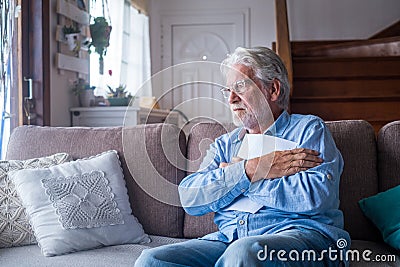 Sad elderly man reading health insurance deal closing looking and reading the medical results. Sick mature senior hugging a sheet Stock Photo