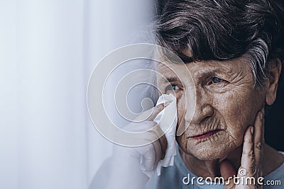 Sad elderly woman wiping tears Stock Photo