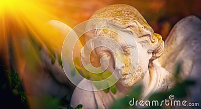 Sad eyes of angel in sunlight. Ancient stone statue. Death, pain and end of life concept Stock Photo