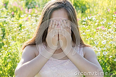 Sad girl covers face with her hands and weeps Stock Photo