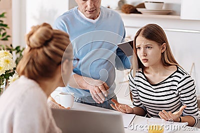 Sad girl doing homework with her parents Stock Photo