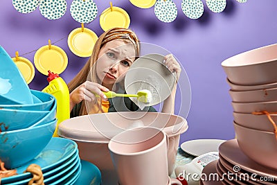 Sad girl feds up cleaning and washing in the kitchen with blue wall Stock Photo