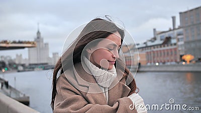 Sad girl freezes on the street Moscow. Person walking along the promenade. Mysterious girl walking by the river. Woman Stock Photo