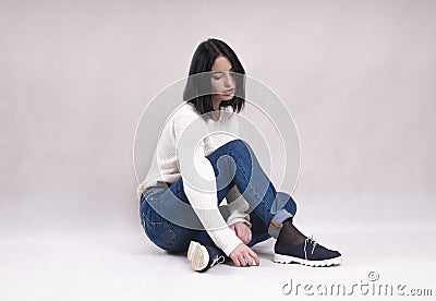 Sad girl sits on the floor in jeans loneliness news depression solitude difficulties Stock Photo