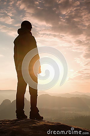 Sad girl stand on the sharp corner of sandstone rock and watch over valley to Sun. Stock Photo