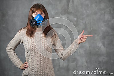 Beautiful young woman in respirator stand on grey background Stock Photo