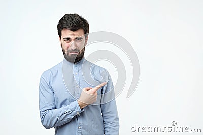 Sad gloomy european boyfriend, whining or crying, frowning and trying to hide tears pointing aside. Stock Photo