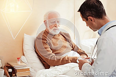 Sad grey-haired male person listening to his doc Stock Photo