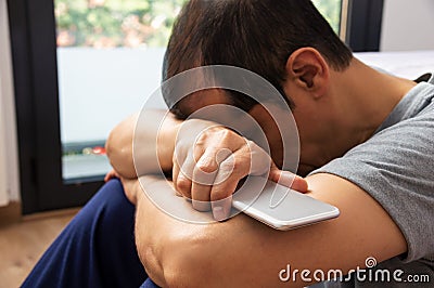 Sad holding a phone lamenting Stock Photo