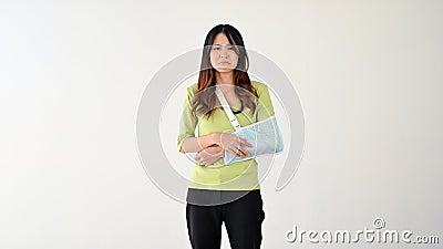A sad and hurtful Asian woman with her broken arm in an arm sling. arm injured, arm pain Stock Photo