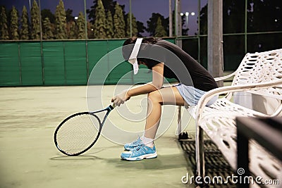 Sad lady tennis player sitting in the court after lose a match Stock Photo