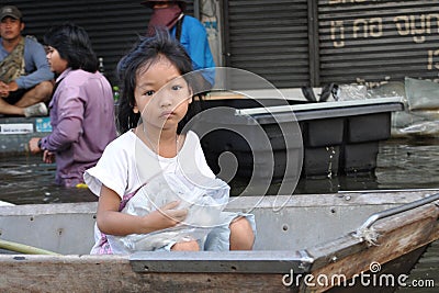 A sad little girl is on a boat, looking at the camera in a flooded street of Bangkok, Thailand, on the 06 November 2011 Editorial Stock Photo