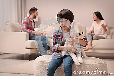 Sad little boy with toy and his arguing parents on sofa in living room Stock Photo