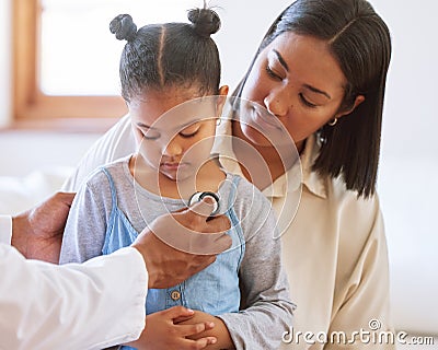 Sad little girl at doctors office. Sick girl sitting with mother while male paediatrician listen to chest heartbeat Stock Photo