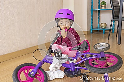 Sad little girl fell to the ground while playing with her bicycle in the floor Stock Photo