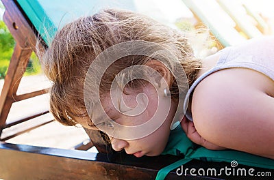 Sad little girl lies with unfortunate eyes Stock Photo