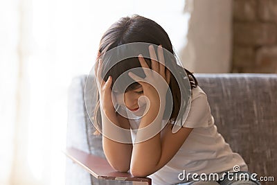 Sad little girl feel lonely sitting alone in armchair Stock Photo