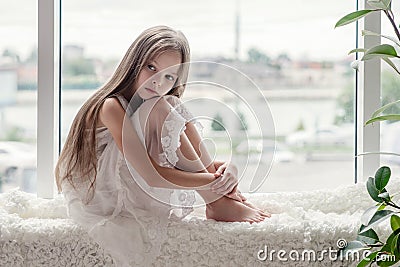 Sad little girl sits alone front of the window Stock Photo