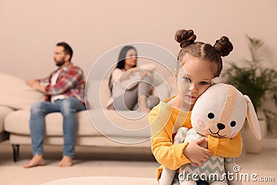 Sad little girl with toy and her arguing parents on sofa in living room Stock Photo
