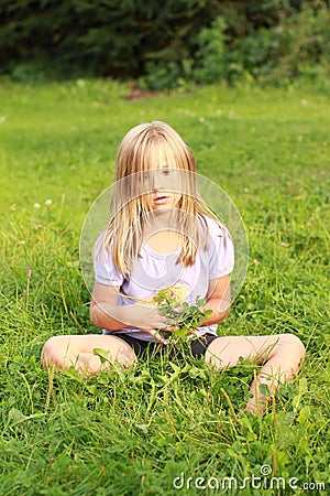 Sad little heary girl on grass Stock Photo
