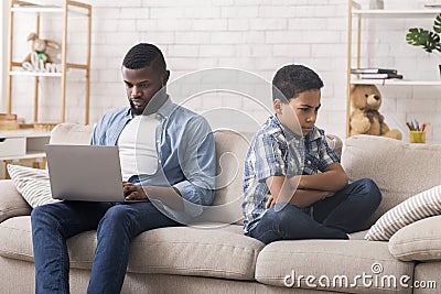 Sad little son offended to father busy with laptop at home Stock Photo