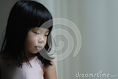 Sad lonely little girl standing beside a window Stock Photo