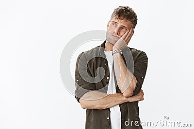 Sad and lonely moody cute european masculine man with beard and blond hair leaning head on palm from boredom looking Stock Photo